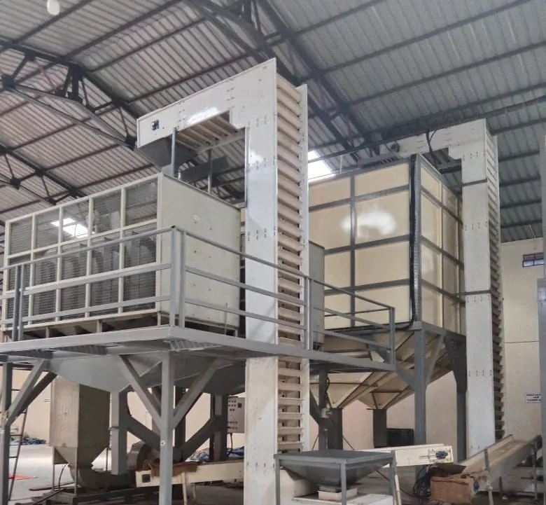 Two bucket elevators either side of a steel access platform, with discharge hoppers below